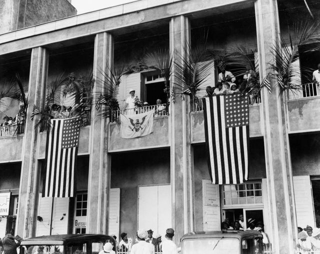 1934년에 촬영된 세인트 토마스에 있는 한 건물 사진. 발코니에는 대형 성조기가 걸려 있으며, 엘리너 루스벨트 당시 미 영부인이 서 있다