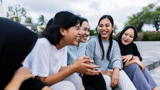 다섯 명의 십대 소녀들이 함께 앉아 웃고 있다.