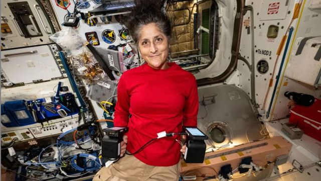  우주선 안에서 양손에 장비를 들고 있는 윌리엄스