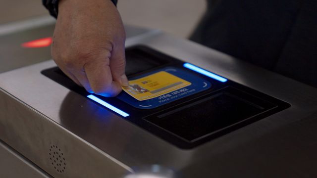 지하철 개찰구에서 한 이용자가 교통카드 단말기에 카드를 찍고 통과하고 있다