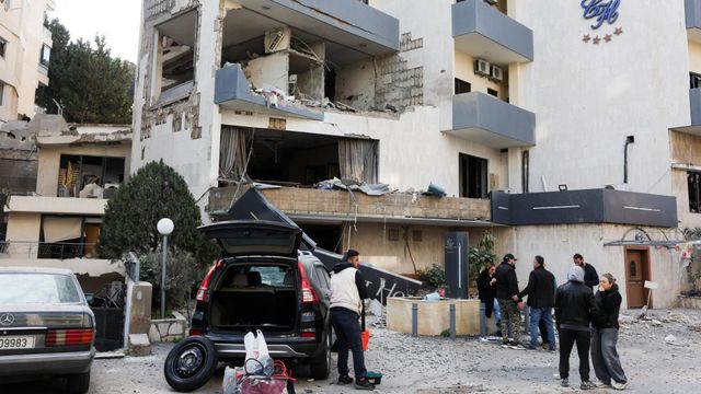 사람들이 공습으로 인해 부서진 건물 주변에 몰려 있다.