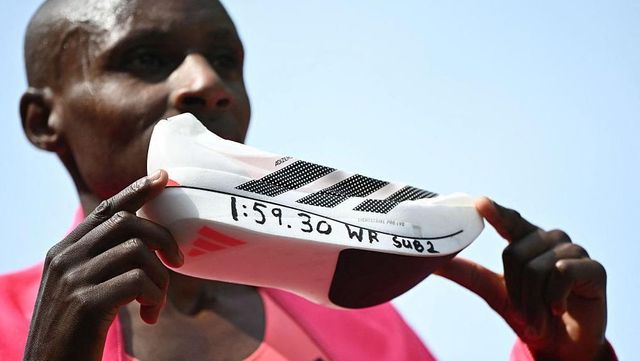 사웨가 자신의 새로운 세계 기록 시간이 적힌 운동화를 들고 있는 모습