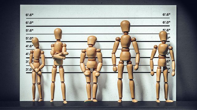 예술적으로 연출된 이미지로, 서로 크기가 다른 베이지색 관절 마네킹 다섯 개가 경찰의 신원 확인 대열처럼 배열되어 있다. 뒤에는 키를 비교할 수 있는 눈금이 표시된 흑백 보드가 있다
