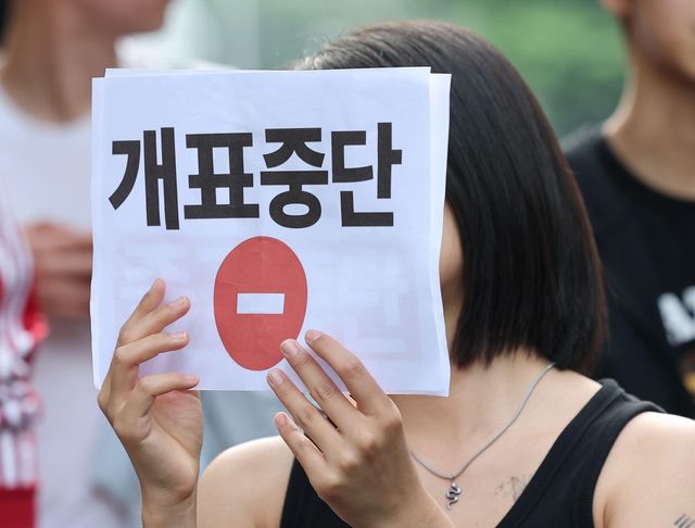 '개표 중단'이라고 적힌 팻말을 든 시민이 투표용지 부족 사태에 항의하는 집회에 참석하고 있다