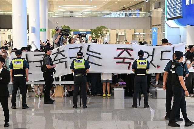 '한국 축구는 죽었다'라고 적힌 대형 현수막을 들고 있는 사람들과 그 앞을 지키고 있는 경찰들