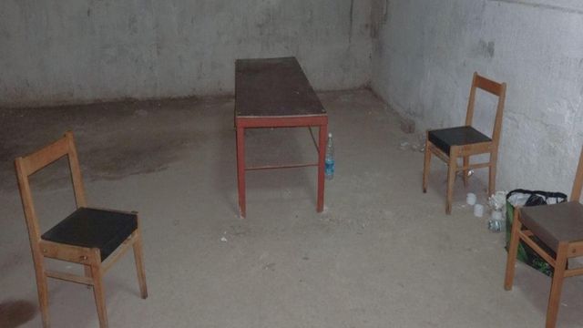 나무의자 몇 개가 있는, 콘크리트 벽과 바닥으로 된 방