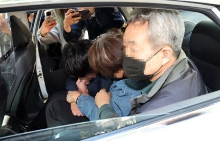 ‘수원 전세사기 의혹’ 사건의 피의자인 정모 씨 일가가 세입자들에 막혀 택시에 고립된 채 고개를 숙이고 있다.ⓒ연합뉴스