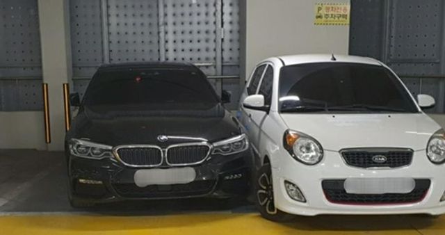주차선을 넘어온 BMW 차량 옆에 경차가 주차돼 있다. BMW 차주는 차를 못 빼 경찰의 도움을 받았다.ⓒ연합뉴스