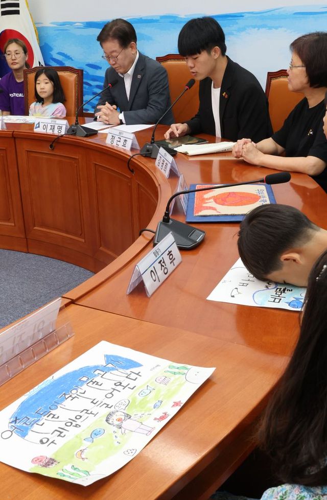 더불어민주당 이재명 대표가 지난 8일 국회에서 열린 후쿠시마 핵 오염수 저지를 위한 아동, 청소년, 양육자 간담회에 참석한 가운데 한 어린이가 책상 위에 얼굴을 숙이고 발언을 듣고 있다.ⓒ 연합뉴스