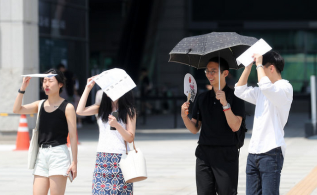 서울 용산구 국립중앙박물관에서 시민들이 종이와 양산으로 햇빛을 피하며 걸어가고 있다.ⓒ뉴시스