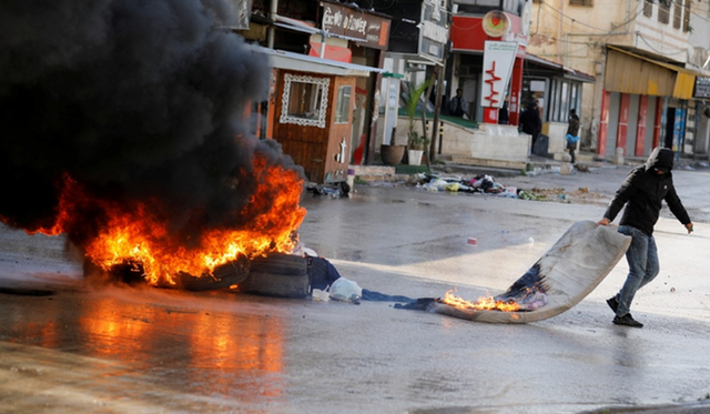 지난해 12월 13일 요르단강 서안 북부 제닌시에서 한 팔레스타인 주민이 불타는 모포로 바리케이트를 치고 있다. ⓒ로이터/연합뉴스