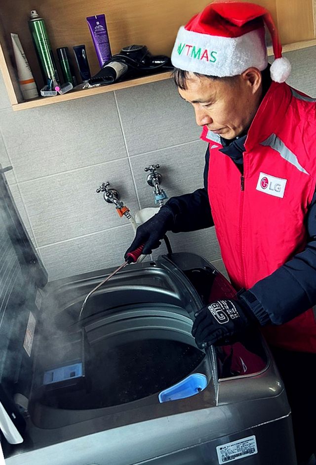 LG전자 서비스 매니저가 복지시설을 찾아 겨울철 동결·동파가 발생하기 쉬운 세탁기를 점검하고 스팀으로 내부를 살균하고 있다. / 사진=LG전자