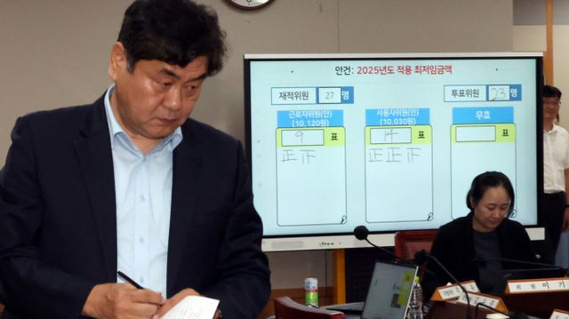 이인재 최저임금위원장이 지난 7월12일 새벽 세종시 정부세종청사에서 2025년도 적용 최저임금이 결정된 뒤 자리로 향하고 있다. 뒤쪽으로 내년도 최저임금은 10030원 결정된 표결결과가 보이고 있다. /사진=뉴시스