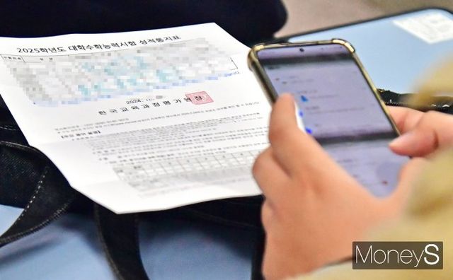▲ 수능 성적통지표를 받아본 수험생, 체점한 점수 비교룰 위해 핸드폰을 열어본다