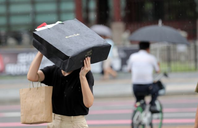 오는 13일 전국에 소나기가 내릴 예정이며 제주에서 시작된 비는 전남권과 경남권 해안으로 확대될 예정이다, 사진은 지난해 8월21일 서울 광화문 사거리에서 갑자기 내린 소나기를 막은 채 발걸음을 옮기는 시민. /사진=뉴시스