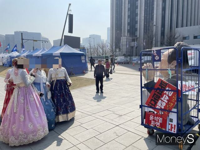 한복을 입은 외국인 관광객이 비상행동 단식 농성 천막 앞에 놓인 윤석열 대통령 모형을 촬영하고 있다. /사진=이소연 기자