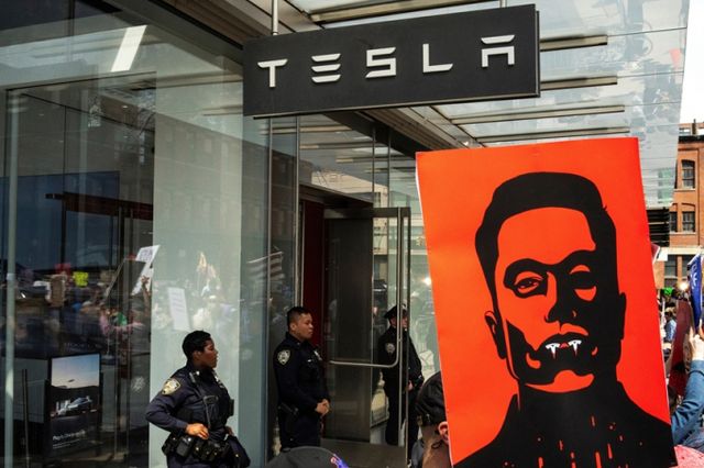 미국 뉴욕 경찰관들이 2025년 3월29일 뉴욕시 테슬라 매장 앞에서 테슬라와 일론 머스크 CEO에 반대하는 시위에 참여한 시위대들을 주시하고 있다./사진=로이터 
