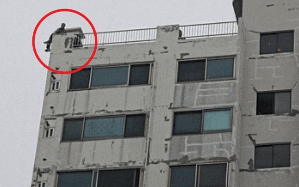 극단적 선택을 시도하려던 것으로 추정되는 남성을 구조한 구급대원 영상이 누리꾼 사이에 화제를 모으고 있다. 사진은 아파트 옥상 난간에 앉아 있는 남성을 구조하는 구급대원의 모습. /사진=보배드림 인스타그램 캡처
