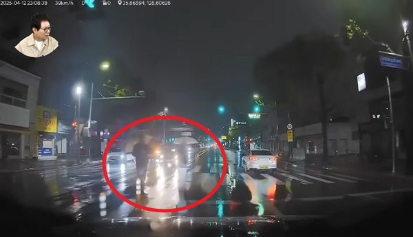 무단횡단하던 남성이 경적을 울린 차를 우산으로 콕 찍는 모습이 공분을 사고 있다. 사진은 무단횡단을 시도하는 남성들의 모습. /사진=유튜브 채널 '한문철 TV' 캡처