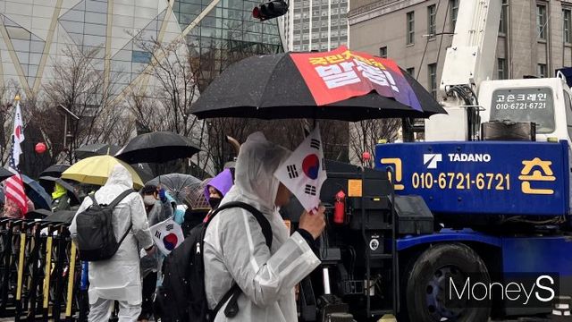  '국민저항권 발동' 플래카드가 붙어있는 우산과 태극기를 든 시민이 거리를 지나가고 있다./사진= 박은서 기자