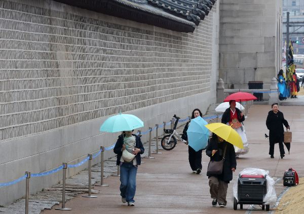 10일은 전국적으로 흐리며 오후까지 '황사비'가 내리겠다. 사진은 서울 종로구 경복궁 돌담 아래로 우산을 쓴 관광객들이 발걸음을 옮기는 모습. /사진=뉴시스