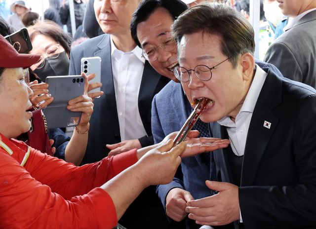 민심을 청취하는 '경청 투어'에 나선 이재명 더불어민주당 대선후보가 10일 경남 함안군 가야시장 반찬가게에서 김치를 맛보고 있다./사진=뉴시스