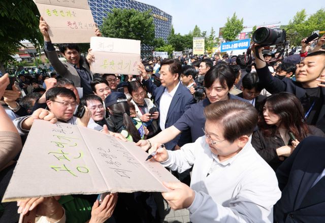  이재명 더불어민주당 대선 후보가 위증교사 사건 항소심과 '대장동·위례·백현동·성남FC' 사건 1심 재판부에도 재판 기일 변경을 신청했다.사진은 민심을 청취하는 '경청 투어'에 나선 이재명 더불어민주당 대선후보가 7일 전북 전주시 완산구 풍남문 인근에서 공판연기를 혼영하는 지지자의 응원 피켓에 사인을 해주는 모습. /사진=뉴시스