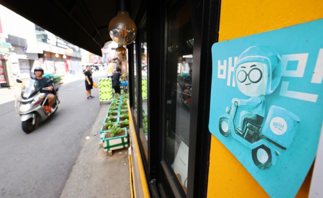 우아한형제들이 더불어민주당 을지키는민생실천위원회 중재로 전국가맹점주협의회, 공정한플랫폼을위한사장협회 등 입점업주단체와 진행하고 있는 사회적 대화를 통해 1만원 이하 주문에 대한 수수료를 전액 면제하기로 합의했다. 서울 시내 한 음식점에 배달 어플 배달의민족 제휴 안내 홍보물이 부착돼 있다. /사진=뉴시스