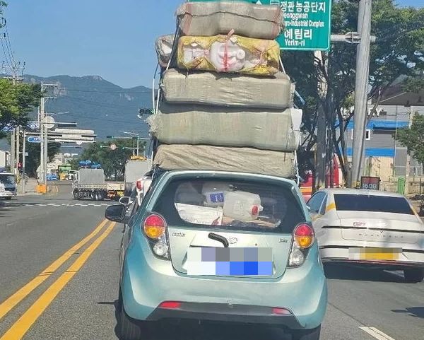 차 위에 짐을 가득 싣고 달리는 마티즈 운전자가 뭇매를 맞고 있다. 사진은 부산 기장군 한 도로를 달리는 마티즈 모습. /사진=온라인 커뮤니티 캡처