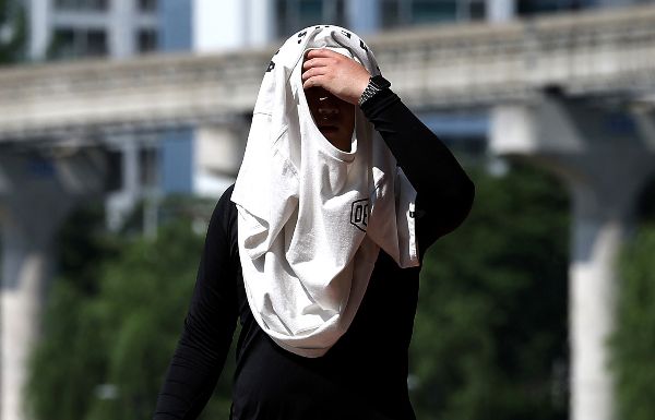 오는 26일은 전국이 대체로 흐리겠다. 사진은 전국이 30도 안팎의 무더운 날씨를 보인 지난 23일 대구 북구 동천교에서 한 시민이 겉옷으로 햇빛을 가리고 있는 모습. /사진=뉴시스