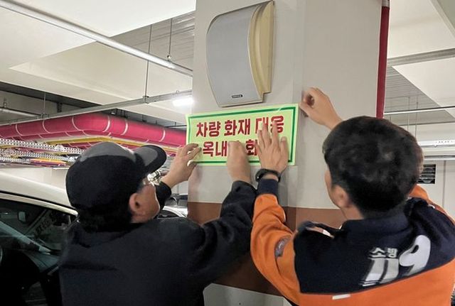 지하주차장에 옥내소화전 스티커를 부착하고 있는 모습