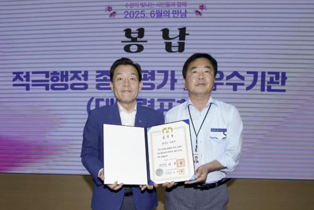 전용기 수원시 법무담당관이 9일 시청 중회의실에서 열린 ‘6월의 만남’ 행사 중에 이재준 수원시장(왼쪽)에게 대통령 표창을 봉납하고 있다.