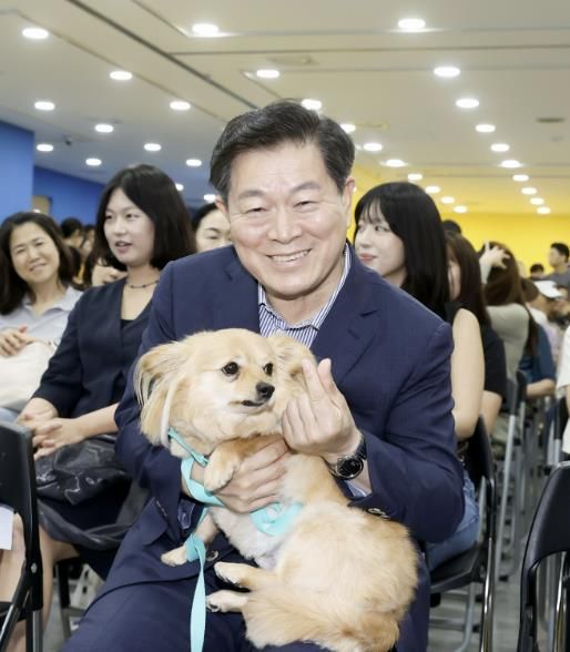 박승원 광명시장이 지난 13일 광명시민회관 전시실에서 열린 반려동물 전시회에 참석해 입양 당일 새 가족을 만난 유기견 '룽지'를 품에 안고 입양의 의미를 알리는 기념사진을 촬영하고 있다.