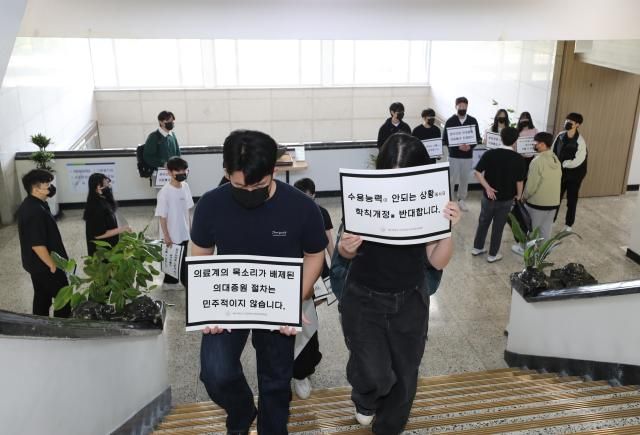 제주대 의대 학생들이 23일 오전 의대 증원에 반대하는 내용의 피켓을 들고 증원 학칙 개정안을 재심의하는 교수평의회가 열리는 대학 본관 회의실로 향하고 있다 사진연합뉴스