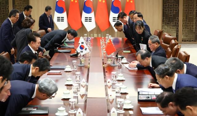 윤석열 대통령이 26일 서울 용산 대통령실에서 열린 회담에서 리창 중국 국무원 총리와 악수 뒤 양국 배석자들과 함께 자리에 앉고 있다 사진연합뉴스
