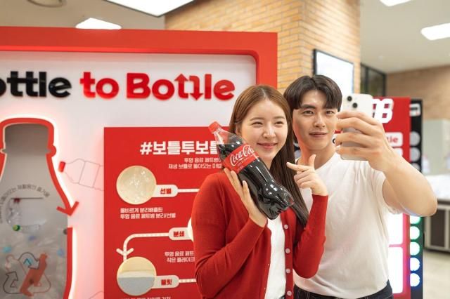 ‘원더플 캠페인’ 시즌5 오프라인 체험존에 마련된 게임존에서 미션을 완료한 참여자가 리워드로 재생원료 10가 활용된 ‘코카-콜라 재생 보틀’을 받고 인증사진을 남기고 있다 사진한국 코카-콜라