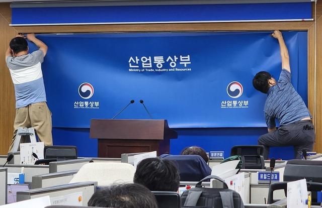 지난 1일 정부세종청사 산업통상부 기자실에서 백드롭 교체 작업이 이뤄지고 있다. [사진=김성서 기자]