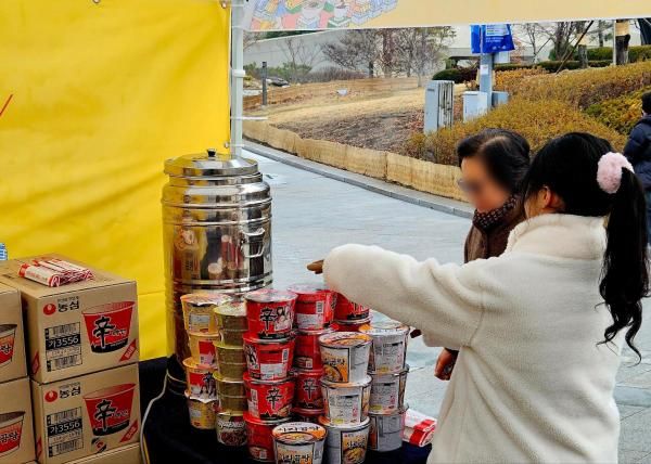 2025 K-푸드 스페셜 페스타 룰렛 이벤트에 당첨된 한 참가자가 농심 라면 제품을 수령하고 있다 사진홍승완 기자