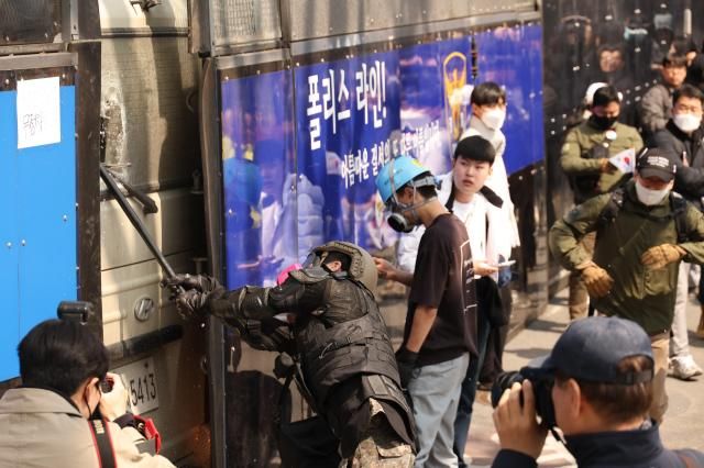 4일 서울 종로구 헌법재판소 인근에서 윤석열 대통령 지지 집회 참가자 중 한 명이 헌재의 윤 대통령 파면 결정에 경찰이 세운 가벽 사이로 보이는 차량을 부수고 있다 사진연합뉴스