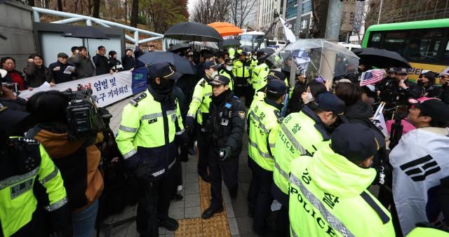 내란 우두머리 혐의로 기소된 윤석열 전 대통령의 첫 형사재판이 열린 14일 서울 서초구 서울중앙지방법원 앞에서 경찰 관계자들이 윤 전 대통령 엄벌 촉구 기자회견을 하는 시민단체와 윤 전 대통령 지지자들을 분리하고 있다 사진연합뉴스