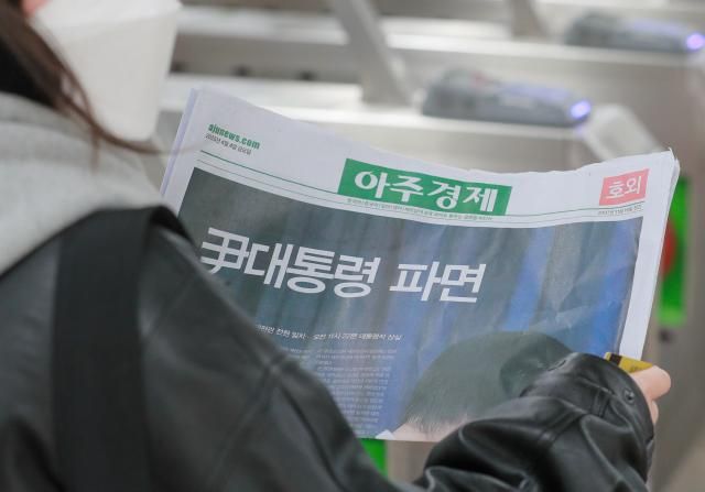 헌법재판소가 윤석열 전 대통령 탄핵심판에 대해 인용을 선고한 4일 서울 종로구 광화문역 출입구에서 시민들이 선고 소식을 실은 아주경제신문 호외를 살펴보고 있다 남궁진웅 기자 timeidajunewscom