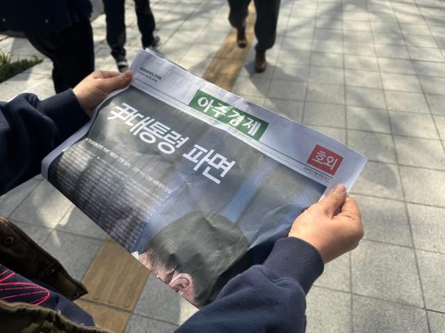 4일 오후 윤석열 대통령 파면 선고 관련 아주경제 호외를 받아든 한 시민이 1면을 읽고 있다 사진송승현 기자