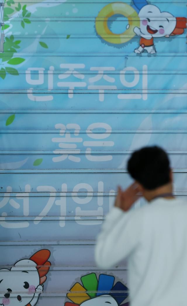 7일 경기도 과천시 중앙선관위 로비에서 직원이 민주주의 꽃은 선거입니다라고 적힌 계단 앞을 지나고 있다 사진연합뉴스