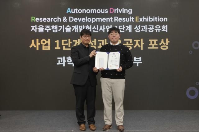 지난 4일 일산킨텍스에서 열린 ‘자율주행기술개발혁신사업’ 1단계 성과공유회에서 카카오모빌리티 홍승환 책임연구원오른쪽이 수상 후 과학기술정보통신부 송창종 디바이스AX혁신팀장왼쪽과 기념사진을 촬영하고 있다 사진카카오모빌리티