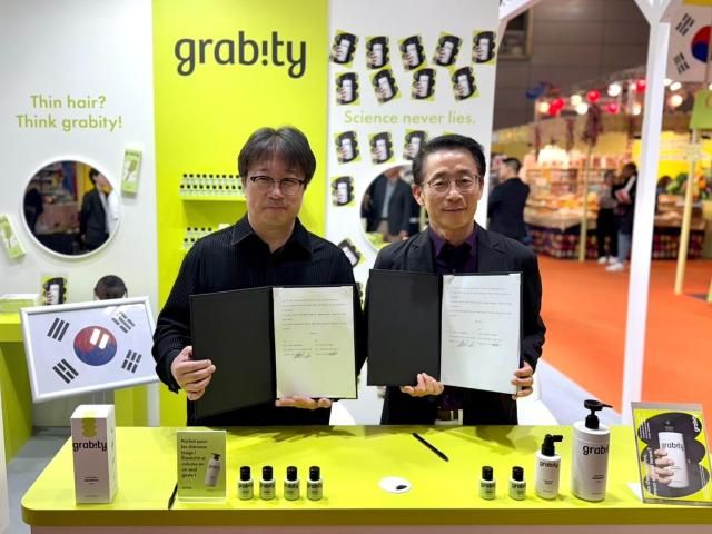 김재겸 롯데홈쇼핑 대표오른쪽와 이해신 폴리페놀팩토리 대표가 11일현지시간 프랑스 파리 포르트 드 베르사유 전시장에서 폴리페놀팩토리의 기능성 탈모 완화 샴푸 그래비티의 수출 독점 계약을 체결한 뒤 기념촬영을 하고 있다 사진롯데홈쇼핑