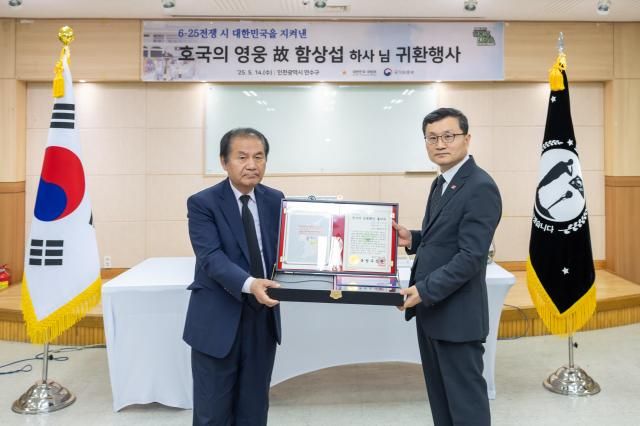 유가족 대표인 아들 함재운씨에게 고 함상섭 하사의 유품 전사자 신원확인 통지서 등이 동봉된 호국의 얼 함을 전달하며 사진을 촬영하고 있는 이근원 국방부유해발굴감식단장 사진국방부 