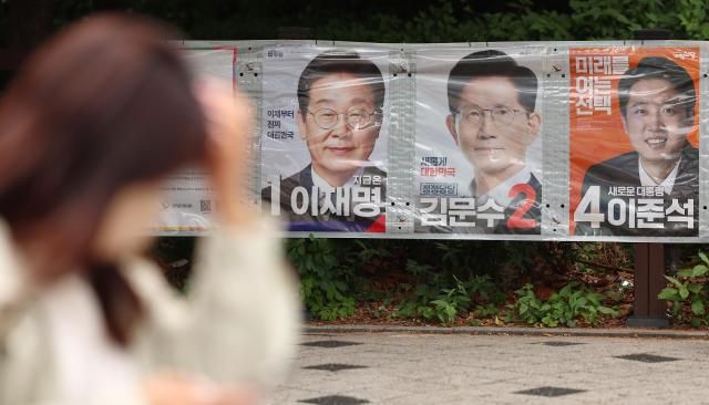 지난 23일 서울 마포구 공덕오거리 인근에 걸린 대선 후보 벽보 앞으로 시민이 지나고 있다 사진연합뉴스