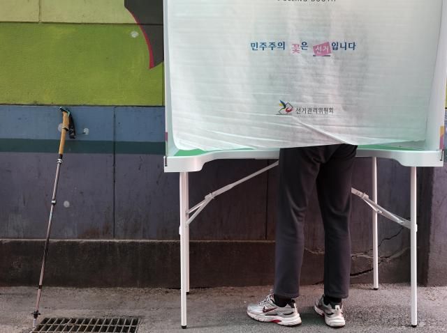 제21대 대통령 선거 사전투표 첫날인 29일 서울 중구 소공동주민센터에 설치된 사전투표소에서 거동이 불편한 유권자가 기표소에서 투표를 하고 있다 사진연합뉴스