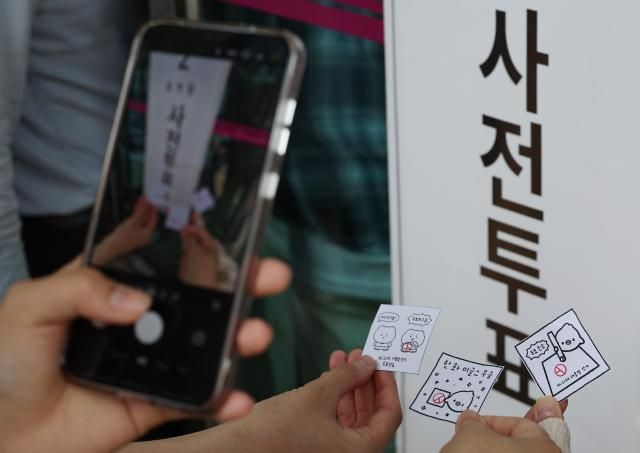 제21대 대통령선거 사전투표 첫날인 29일 서울 강남구 삼성2동주민센터에 마련된 사전투표소 앞에서 시민들이 투표 도장이 찍힌 그림을 들고 기념 촬영을 하고 있다 사진연합뉴스
