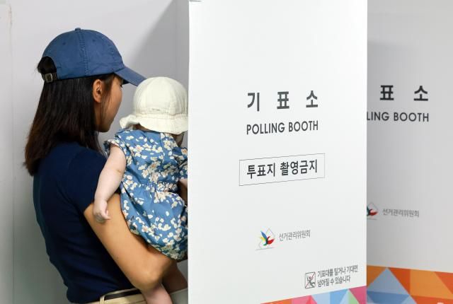 제 21대 대통령 선거 사전투표 둘째날인 30일 서울 관악구 낙성대동주민센터에 마련된 낙성대동사전투표소에서 아이를 안은 유권자가 투표하고 있다 사진연합뉴스